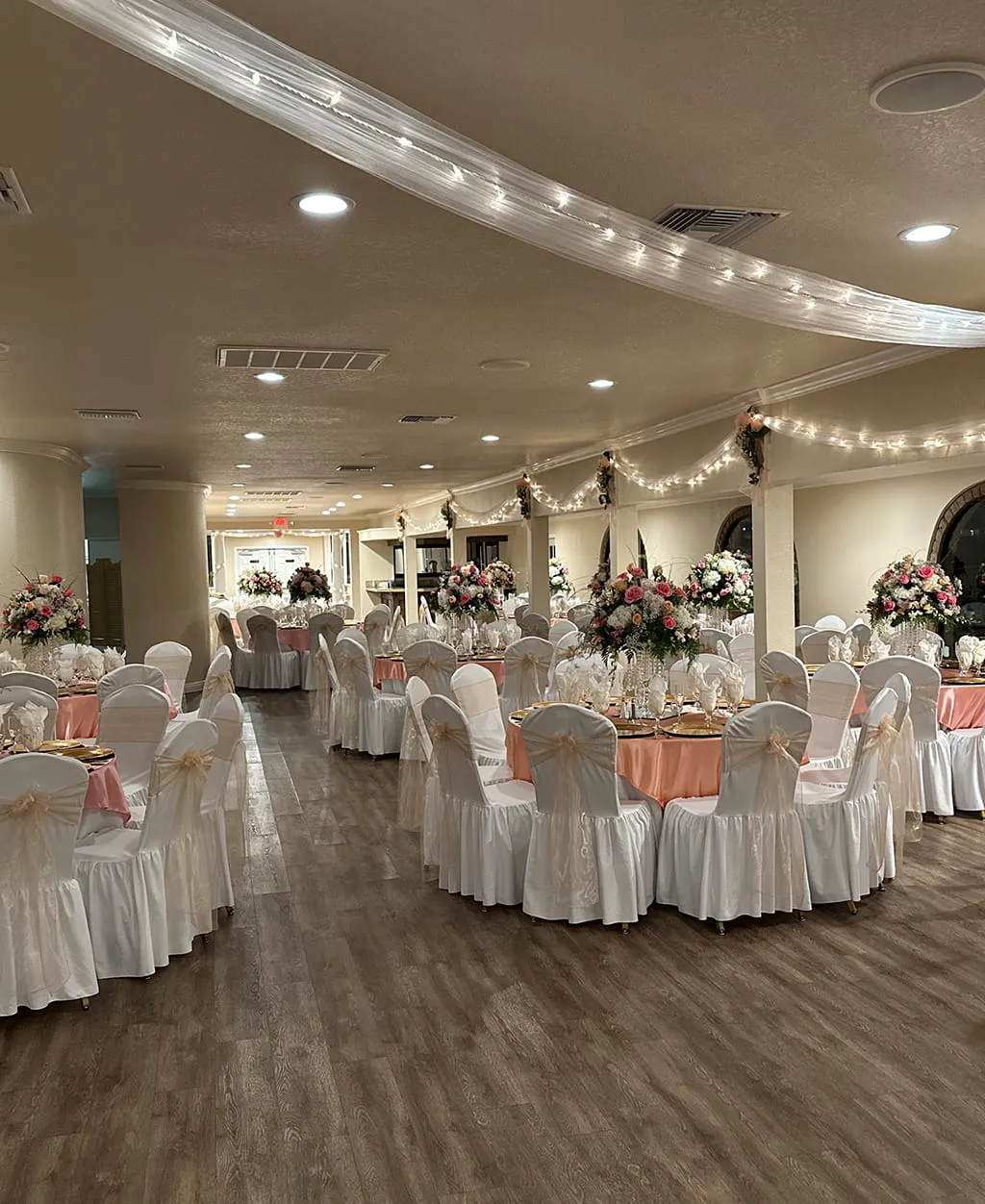 Elegant reception hall with pink floral centerpieces and table decor at Orangecrest Club