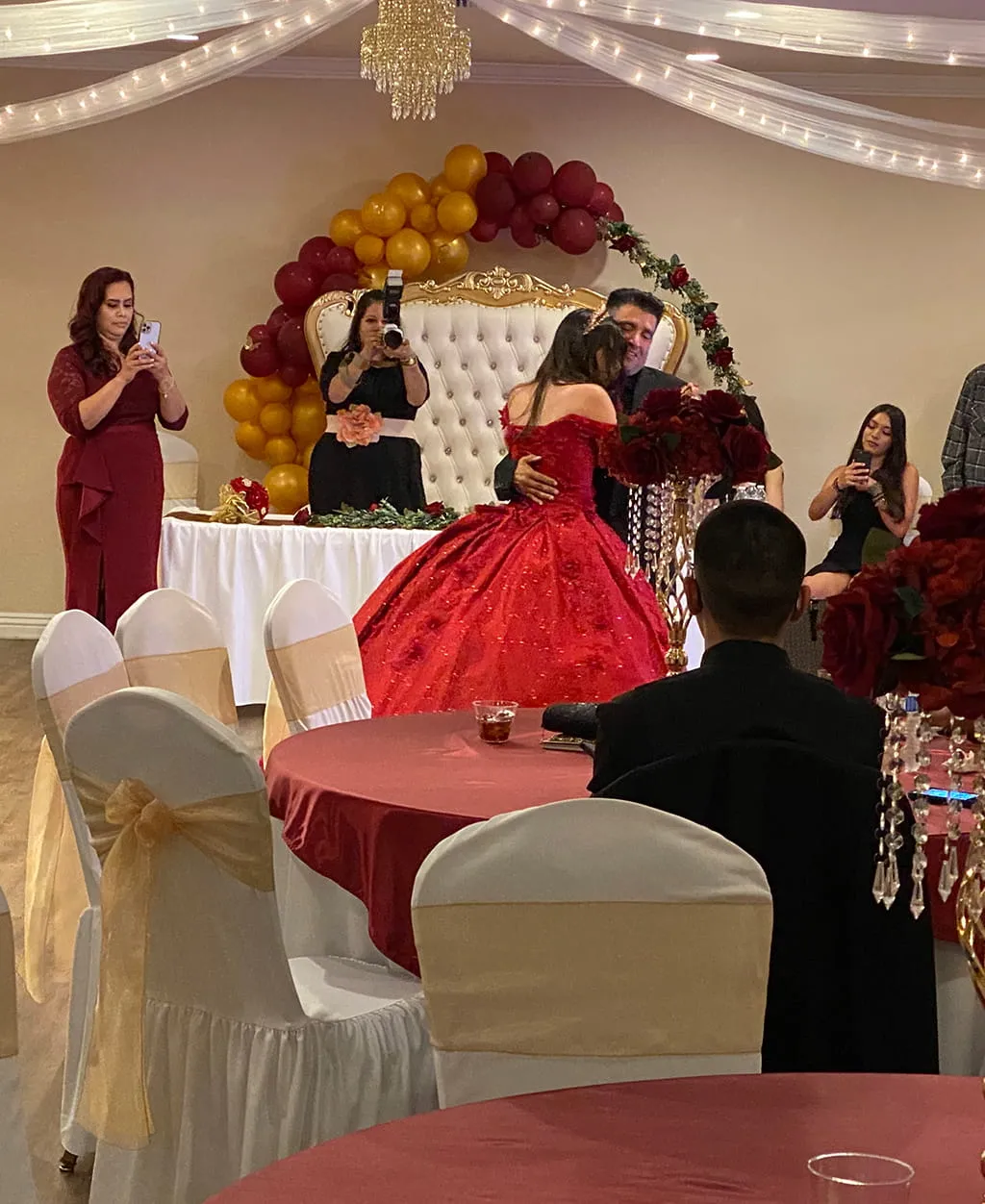 Quinceanera celebration with red dress and elegant stage setup at Orangecrest Club