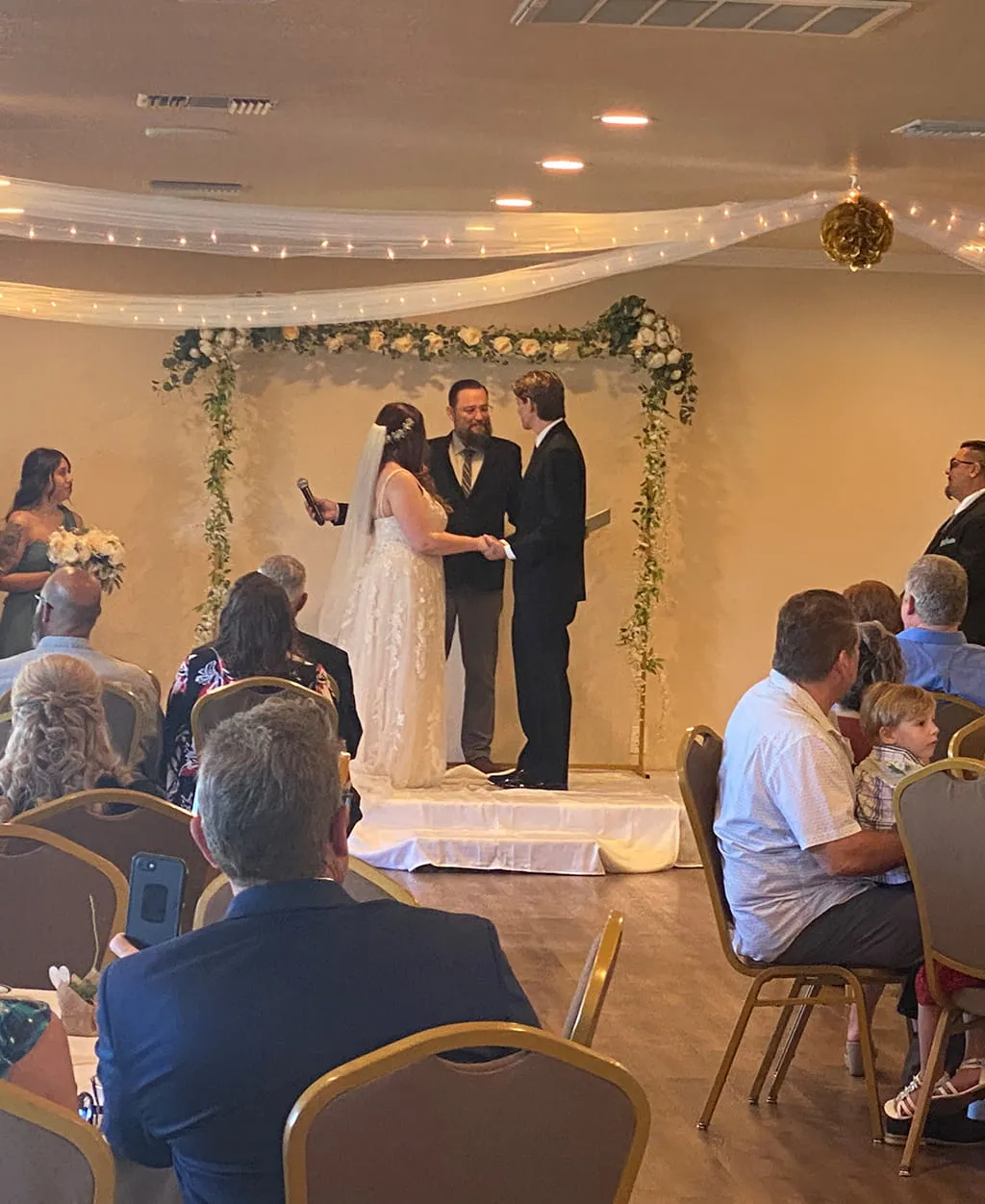 Wedding couple exchanging vows on decorated ceremony stage at Orangecrest Club