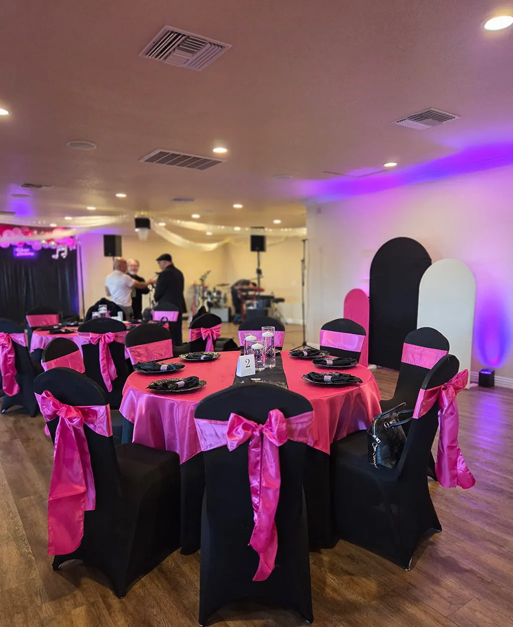 Pink and black party themed table setup with stage lighting at Orangecrest Club