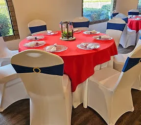 Round banquet table with red linen and navy chair sashes inside Orangecrest Club event venue