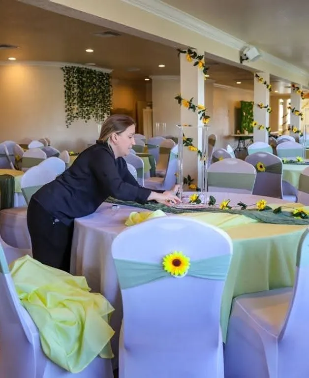 Event staff setting up wedding reception tables with sunflower decor at Orangecrest Club private event venue